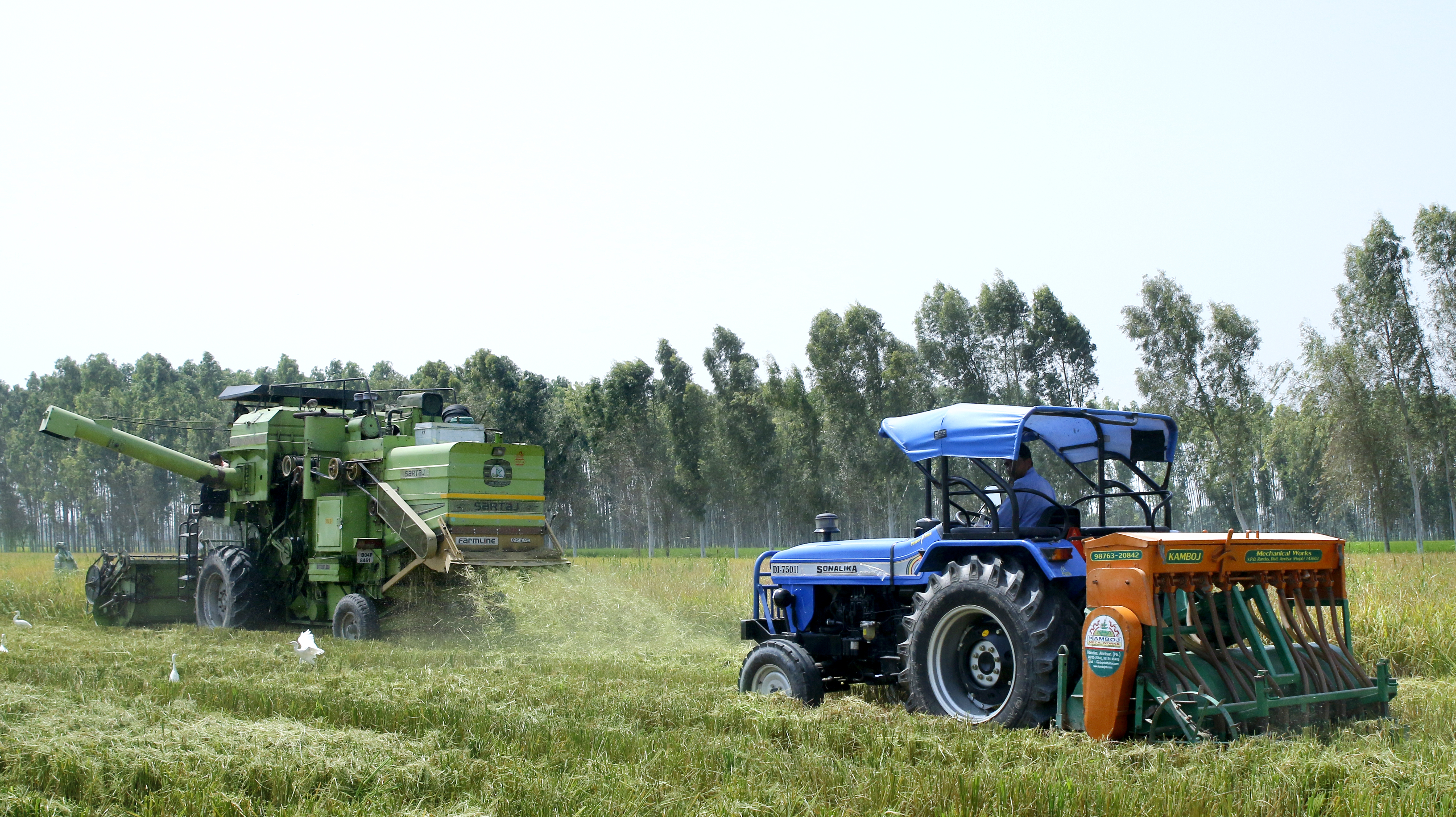 A combine harvester (left) equipped with the Super Straw Management System, or Super SMS, works alongside a tractor fitted with a Happy Seeder. (Photo: Sonalika Tractors)