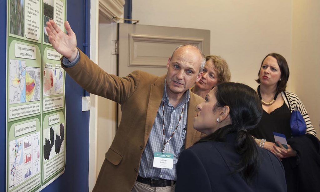 David Hodson, CIMMYT senior scientist (L), describes the challenges posed by wheat rust to Priti Patel, Britain's international development secretary, during the Grand Challenges Annual Meeting in London. Handout/DFID