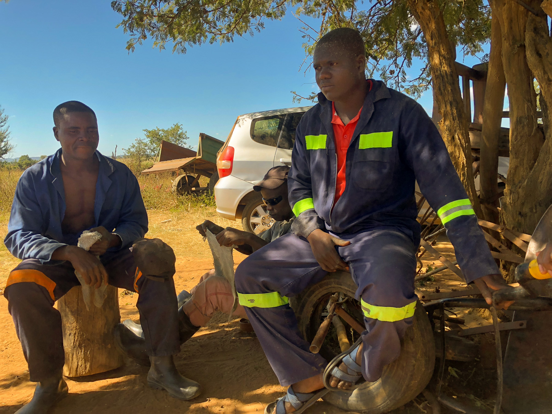 Masimba Mawire, 30, and Gift Chawara, 28, take a break from shelling and rest under a tree. The small car behind was bought by Chawara with his profits earned from the mechanization service business. (Photo: Matthew O’Leary/CIMMYT)