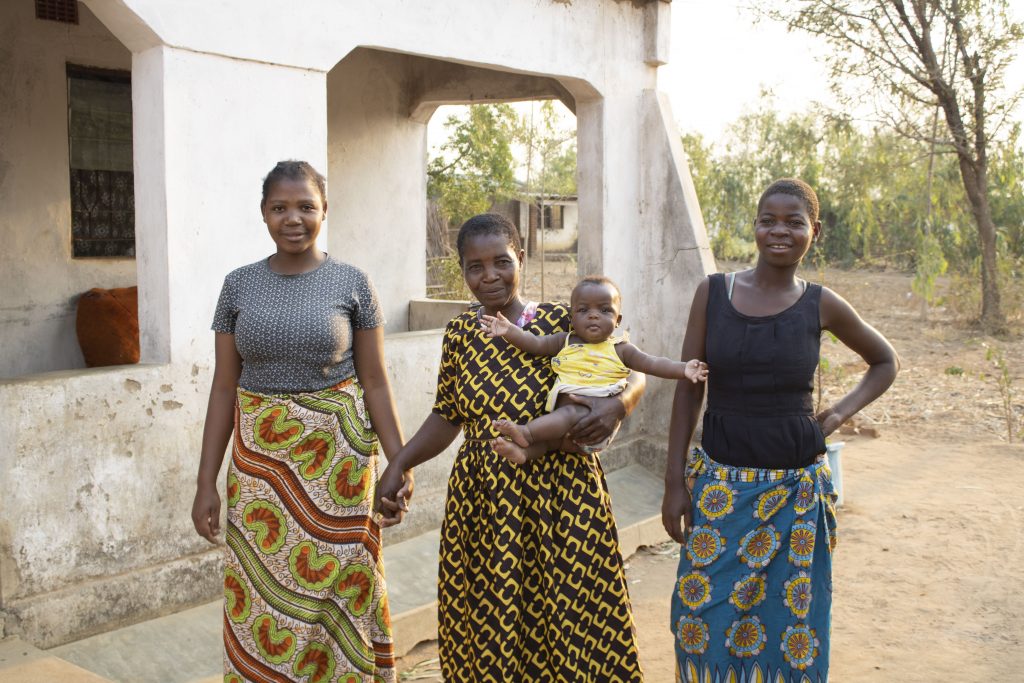 Lughano Mwangonde (center) holds her granddaughter and stands for a portrait with her daughters. (Photo: Shiela Chikulo/CIMMYT)