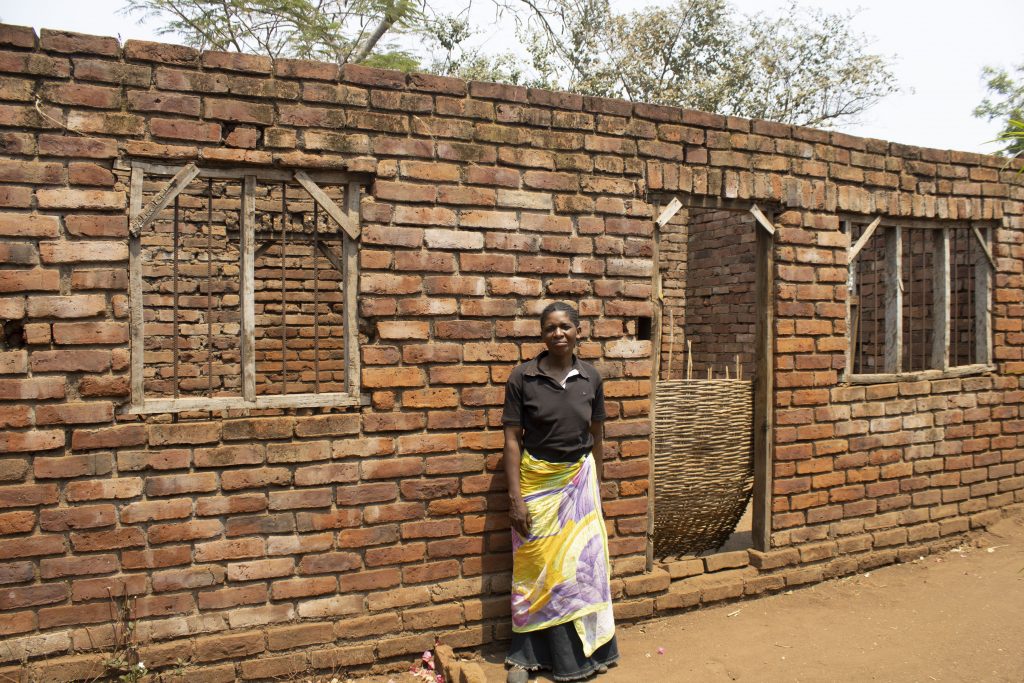 Through surplus sales of maize grain, pigeon pea and groundnuts over the past 12 years, Mary has generated enough income to build a new home. Nearing completion, she has purchased iron sheets for roofing this house by the end of 2019. (Photo: Shiela Chikulo/CIMMYT)