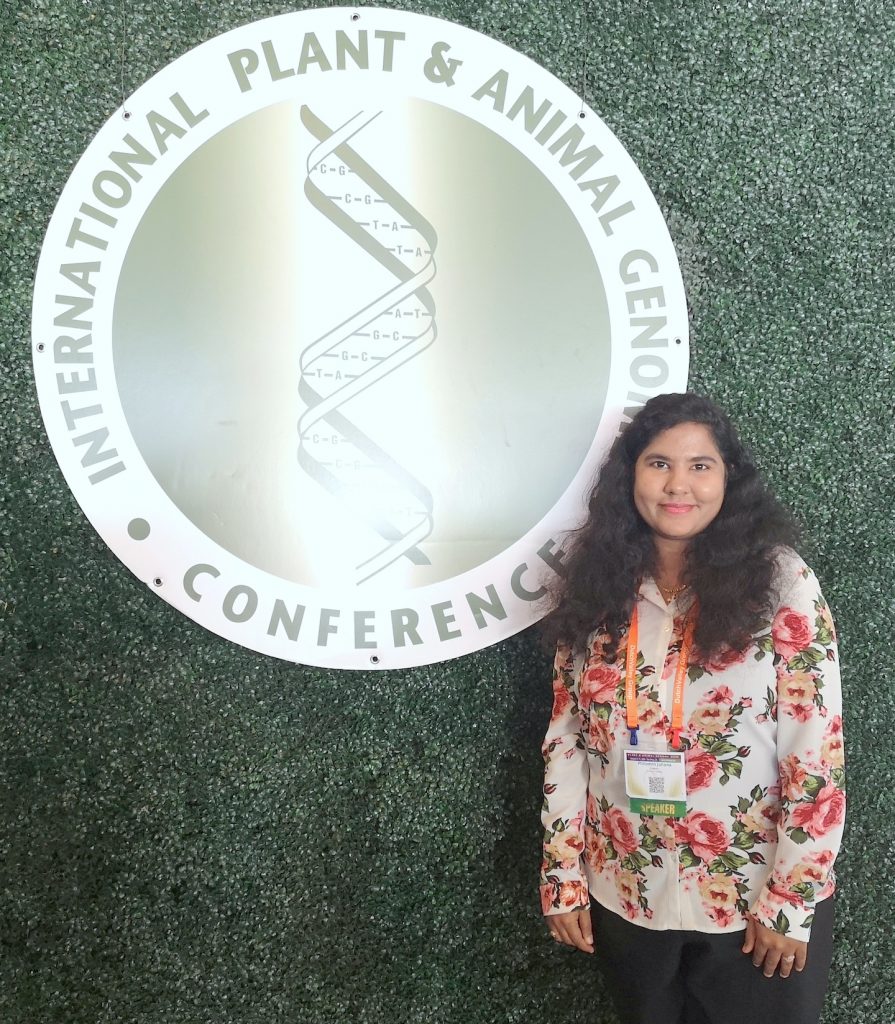 Philomin Juliana stands next to the logo of the PAG conference. (Photo: CIMMYT)