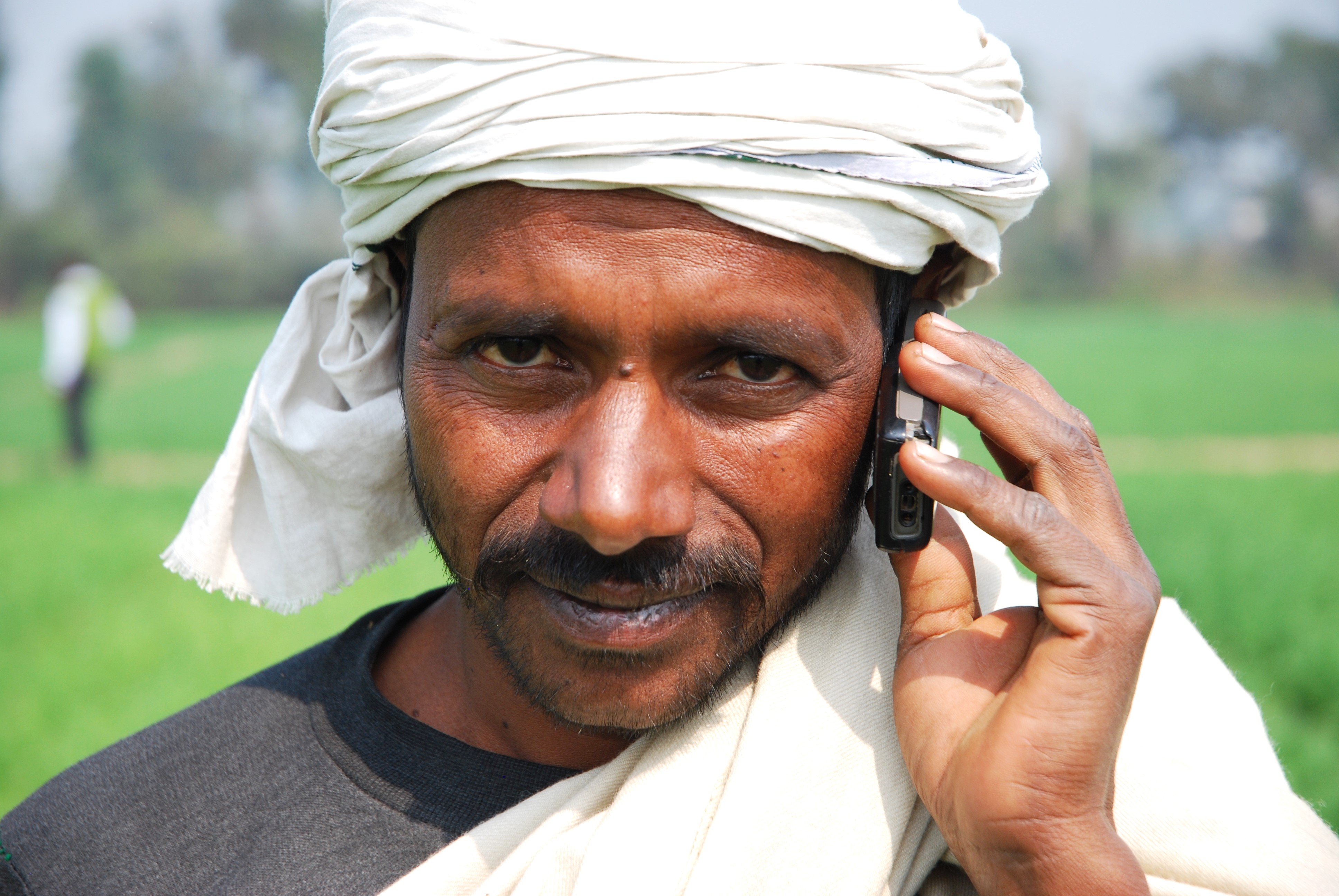 Farmer speaks on mobile phone in field.