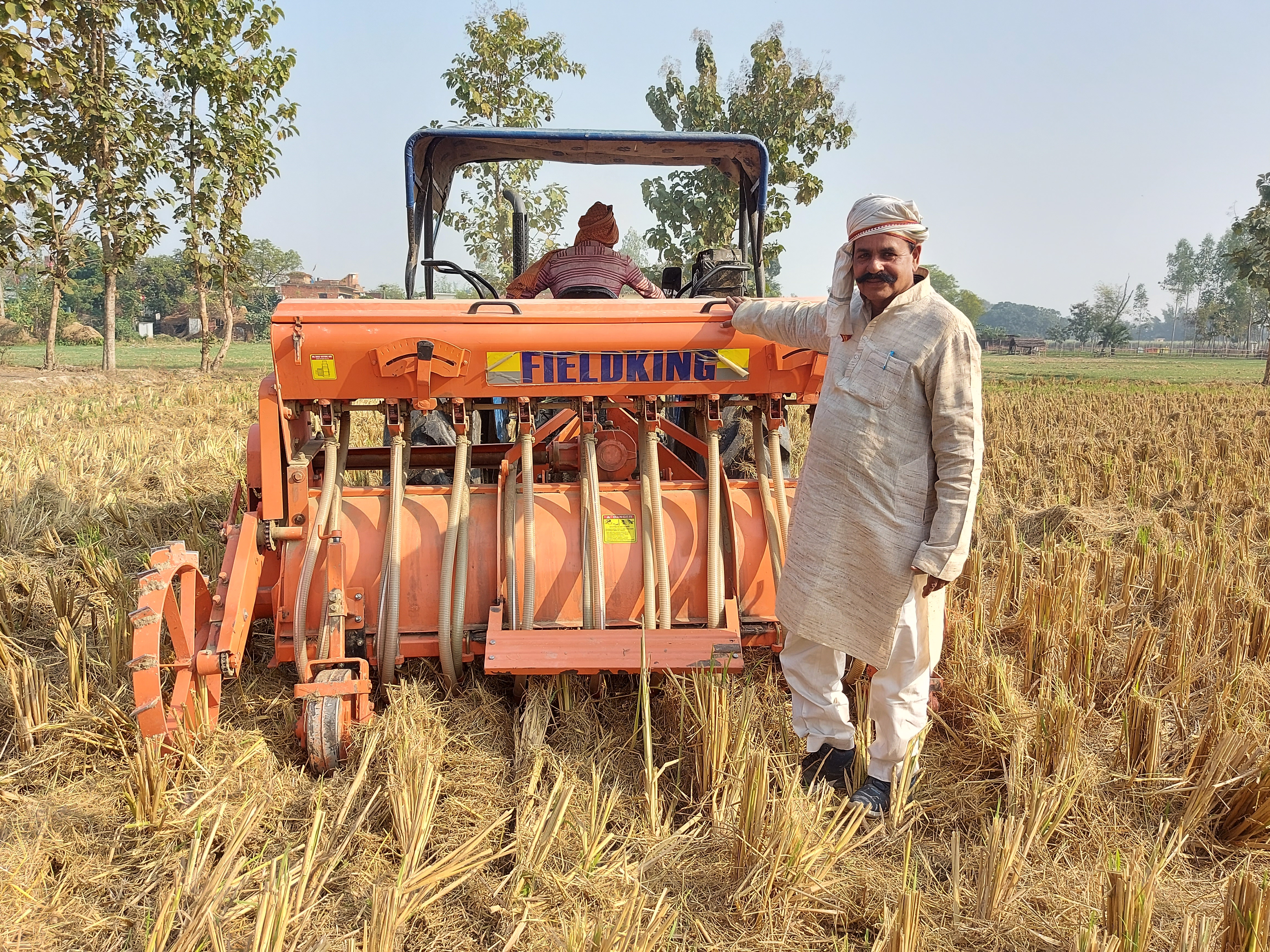 Surender Prasad stands next to his Happy Seeder-mounted tractor in Uttar Pradesh, India. (Photo: Nima Chodon/CIMMYT)