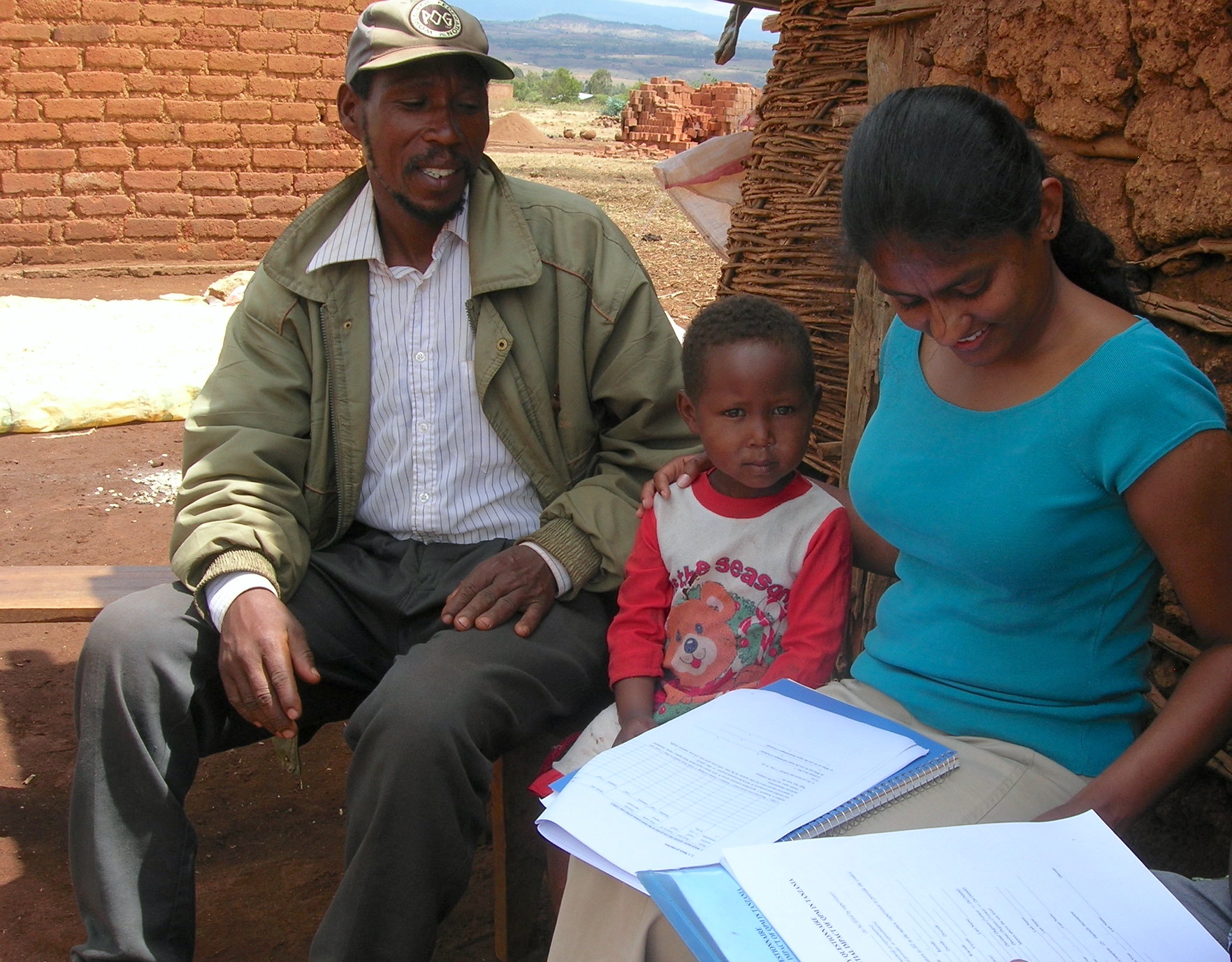 Nilupa Gunaratna (derecha), estadística de la Fundación Internacional de Nutrición, ayuda a un agricultor y a su hija a rellenar un formulario de encuesta sobre el maíz QPM como parte del proyecto QPM Development en Karatu, Tanzania. (Foto: CIMMYT)
