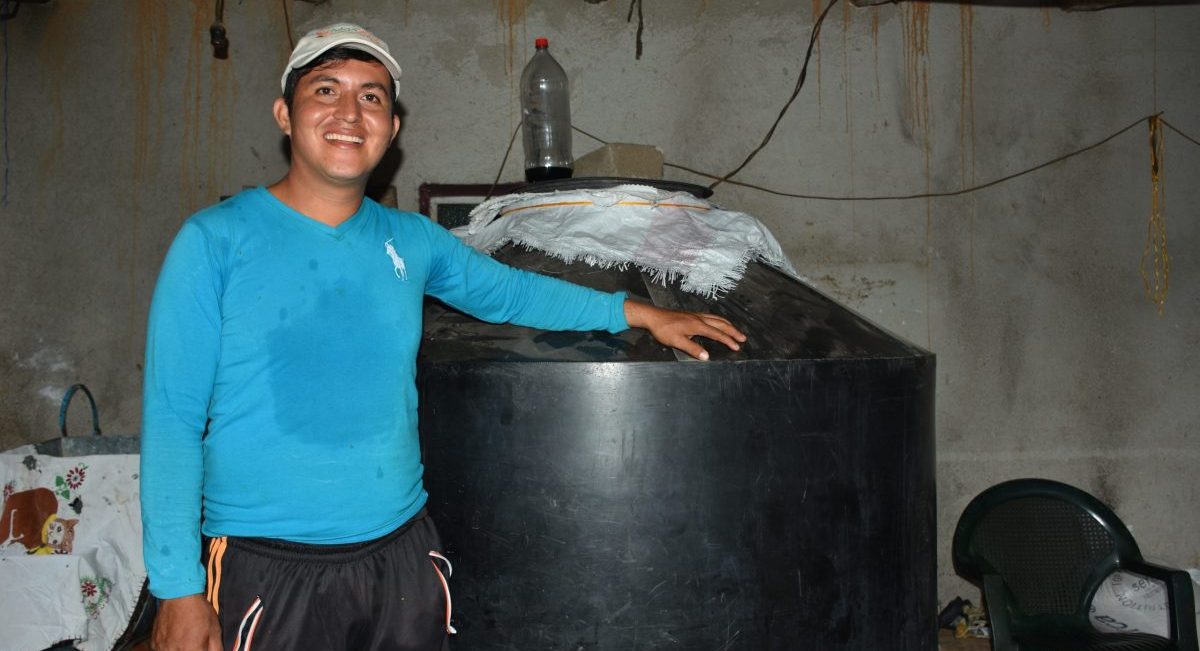 Álvaro Martínez, hijo del señor Anastacio, junto a contenedores donde almacena granos de forma hermética. (Foto: Fernando Morales / CIMMYT)