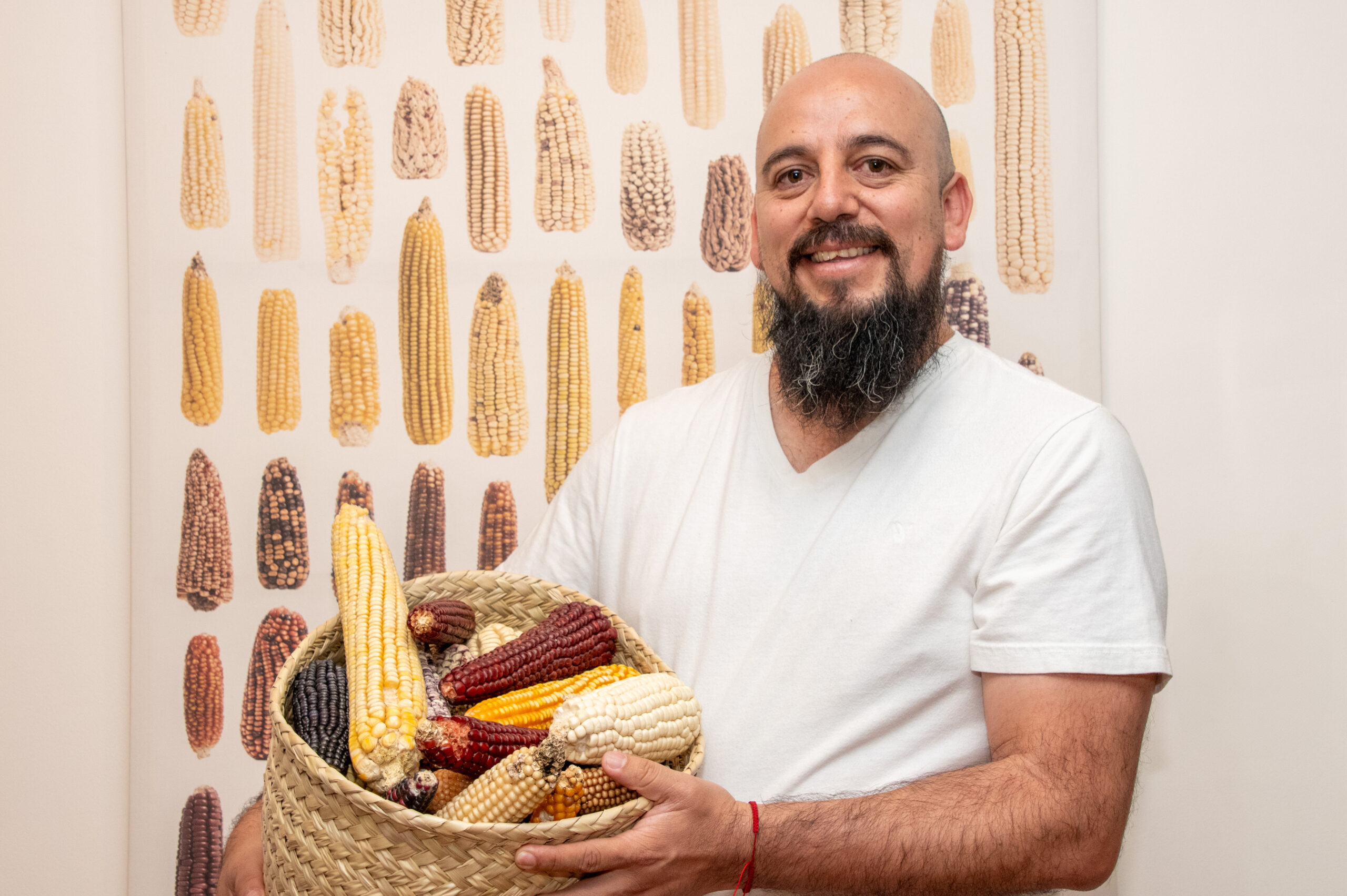 Cristian Zavala, especialista del Banco de Germoplasma del CIMMYT, sostiene una canasta con maíces nativos, símbolo de la riqueza genética que custodia la institución para el presente y el futuro de la alimentación. (Foto: Jenifer Morales/CIMMYT)