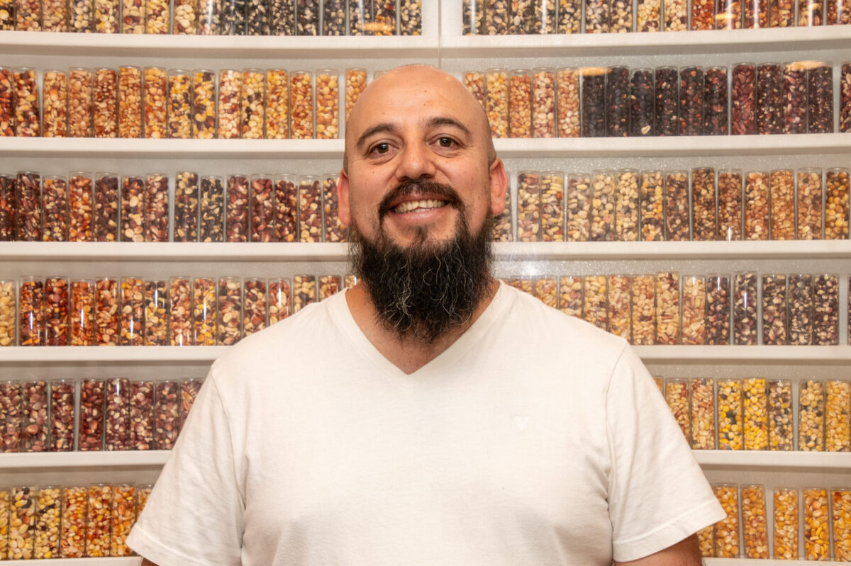 Cristian Zavala, especialista del Banco de Germoplasma del CIMMYT, frente a una muestra representativa de la diversidad de maíces resguardados por la institución. (Foto: Jenifer Morales/CIMMYT)