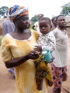 Throughout the developing world, 32% of children under the age of five are stunted and 20% are underweight. Improving the quality of protein in maize can help alleviate this problem in areas where people eat a lot of maize. Here a mother feeds her child QPM during a QPM feeding program hosted by Self-Help International in Ghana.