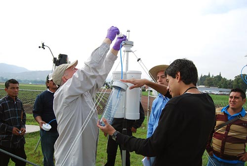 Frieder Hofmann demonstrates how to rinse the pollen from a trap, with Seed Health Laboratory research assistant, Benjamin Asael Martínez, holding the collection bottle.