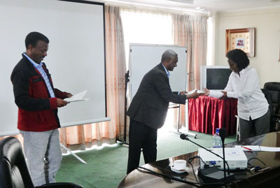Ms. Elsa Asfaha (right), Manager, Alamata Agroprocessing, receives her certificate from Tafesse Gebru (middle), the Chief Executive Officer of the Ethiopian Seed Enterprise, while Adefris Teklewold (left), NuME project leader, looks on.