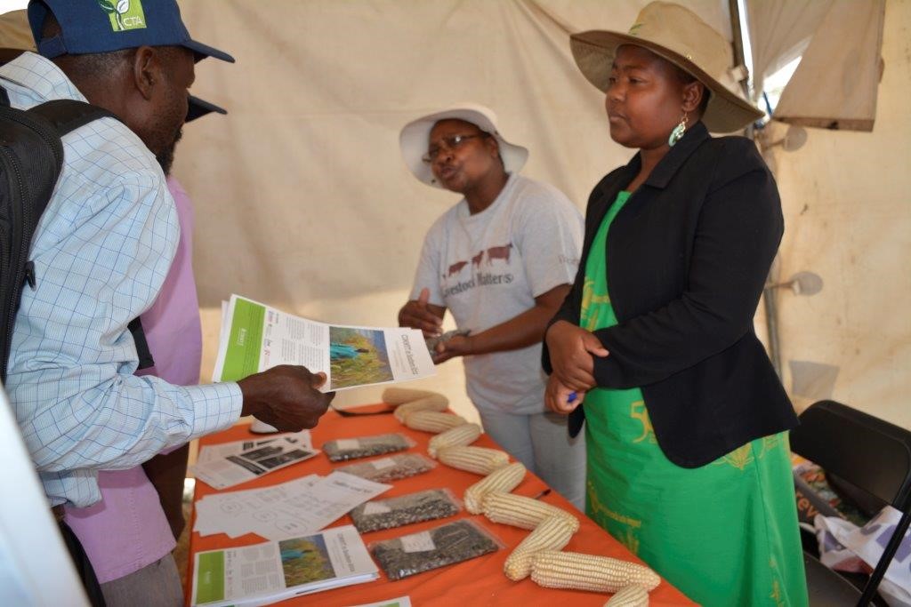 International Livestock Research Institute (ILRI) research officer Irenie Chakoma (extreme right) and CIMMYT research associate Angeline Mujeyi are inundated by requests for information from smallholder farmers at the Mutoko seed fair. Photo: J. Siamachira/CIMMYT.